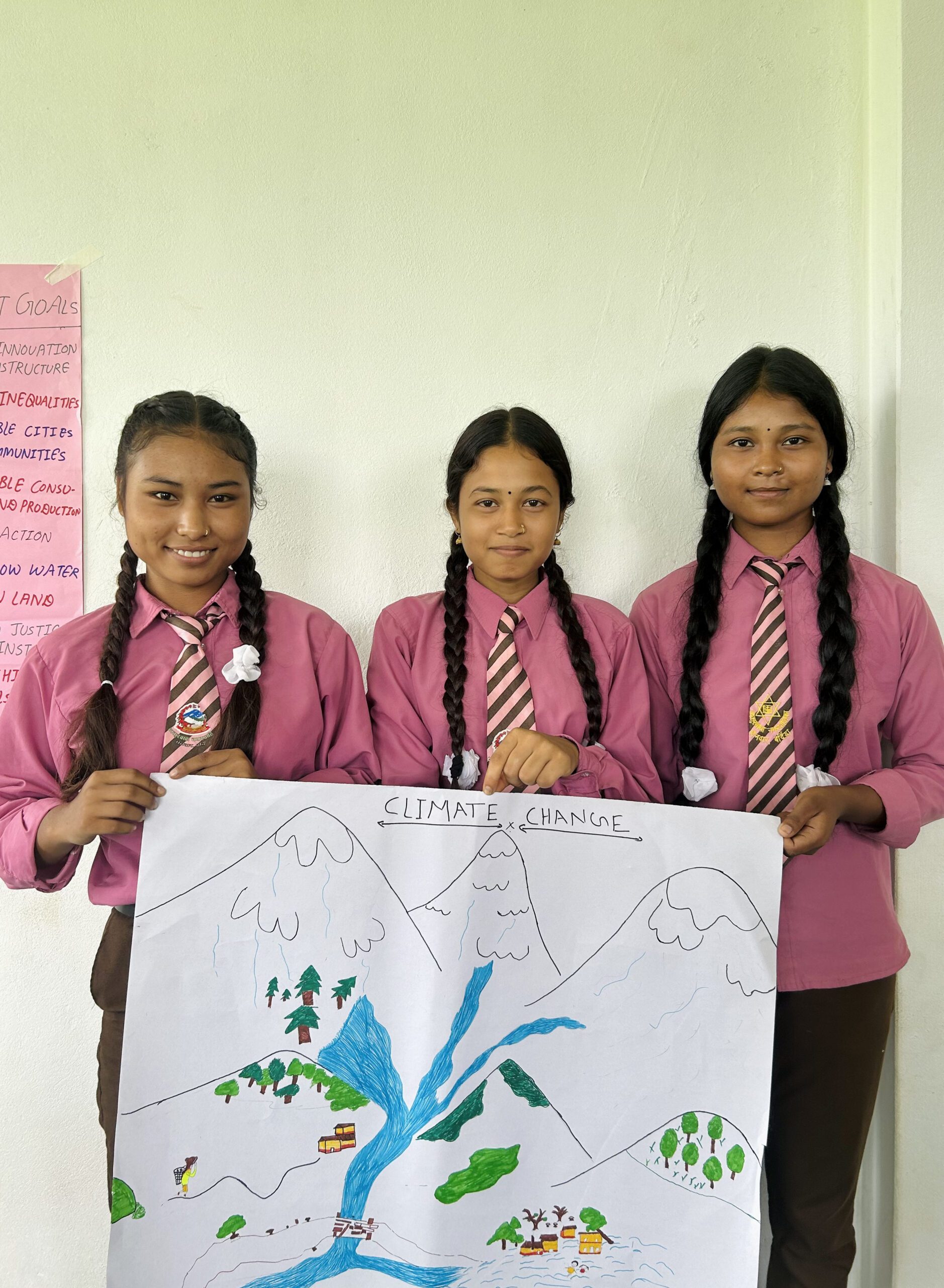 3 girls in school uniform hold a poster they have created during their climate workshop in Nepal