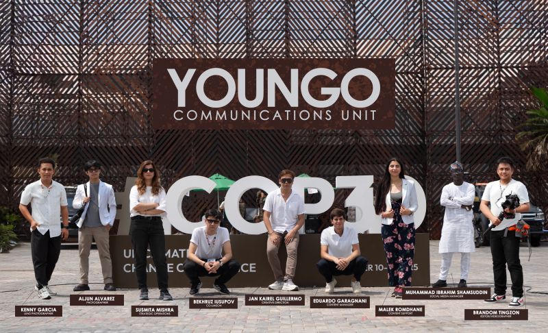 The YOUNGO communications unit, standing infront of the COP30 wall with their name hung behind them