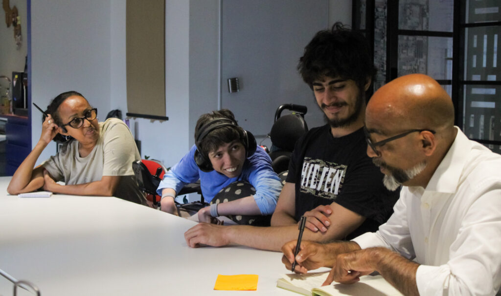 Four people sat at a desk at a PGM meeting